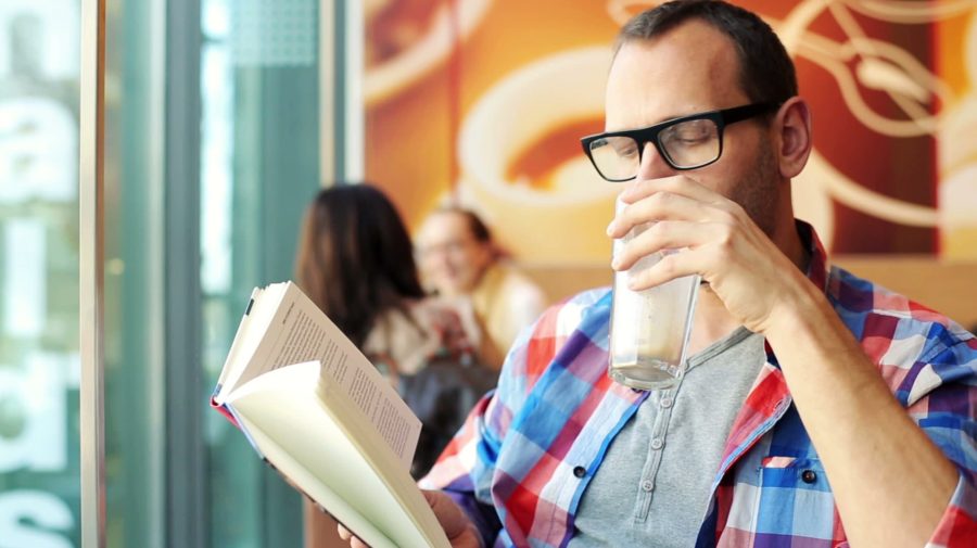 stock-footage-young-hipster-reading-book-drinking-coffee-in-cafe1