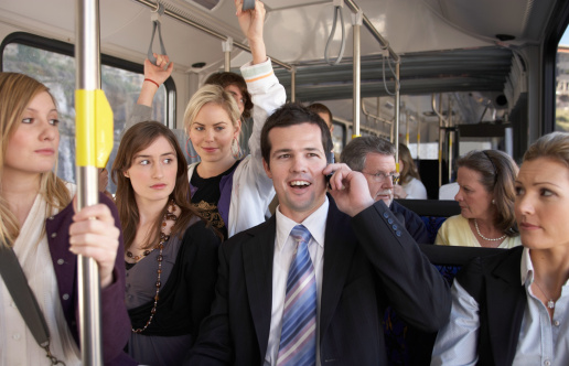 Businessman using mobile phone, laughing on bus