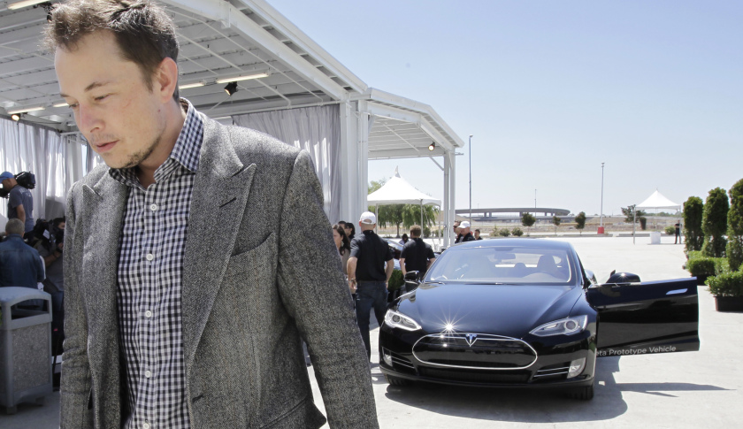 Tesla CEO Elon Musk walks past the Tesla Model S after a news conference at the Tesla factory in Fremont, Calif., Friday, June 22, 2012. The first Model S sedan car will be rolling off the assembly line on Friday. (AP Photo/Paul Sakuma)