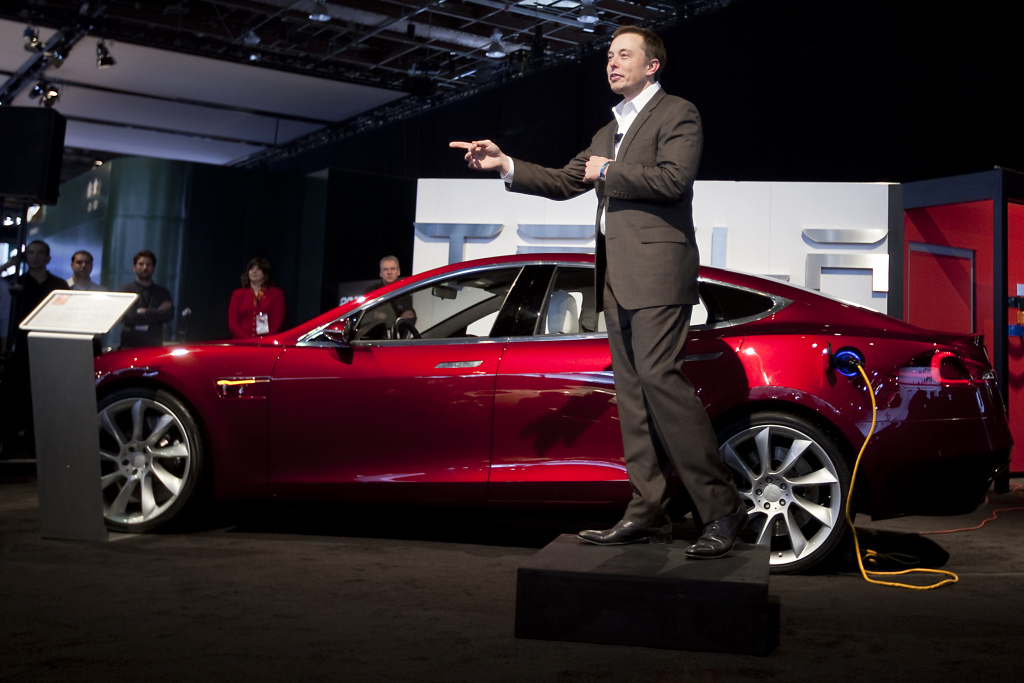 Elon Musk, chairman and chief executive officer of Tesla Motors Inc., speaks in front of a Tesla Model S electric car on day two of the 2010 North American International Auto Show in Detroit, Michigan, U.S., on Tuesday, Jan. 12, 2010. The 2010 Detroit auto show runs through January 24 and features 60 new vehicle premieres. Photographer: Daniel Acker/Bloomberg via Getty Images