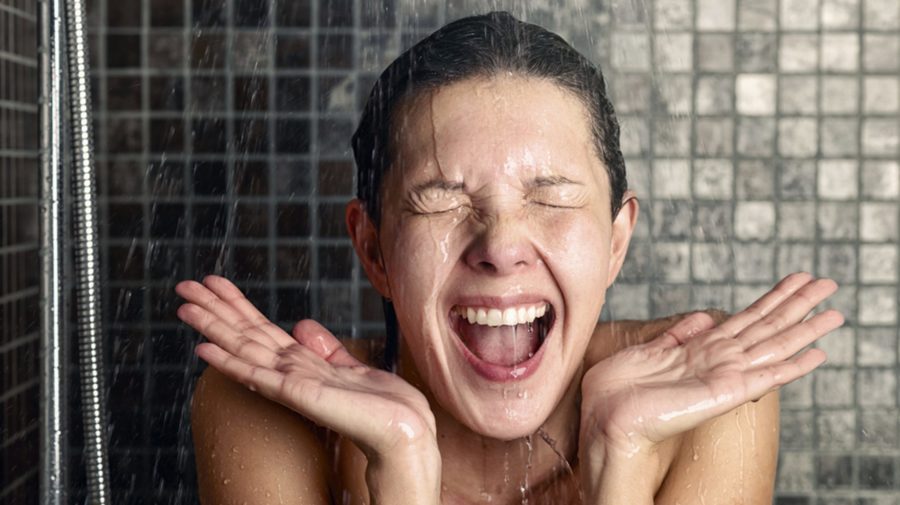 Young woman reacting in shock to cold shower water