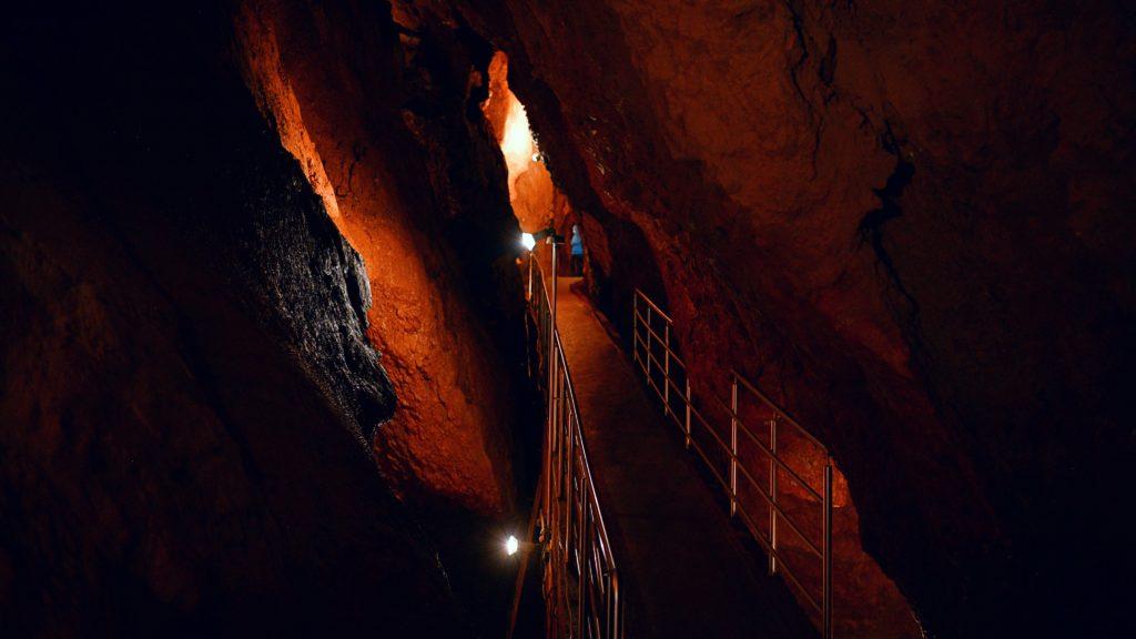 Ochtinská aragonitová jaskyňa je sústava priepastí a útesov, popretkávaná malými mostíkmi s tlmeným osvetlením.