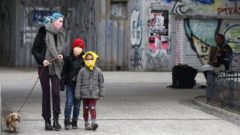 Na snímke je žena s detmi na ulici v rúškach.