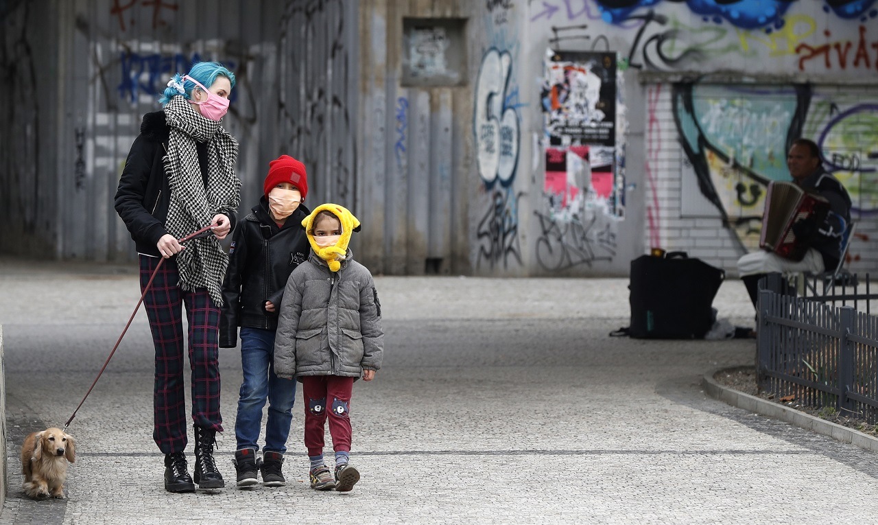 Na snímke je žena s detmi na ulici v rúškach.