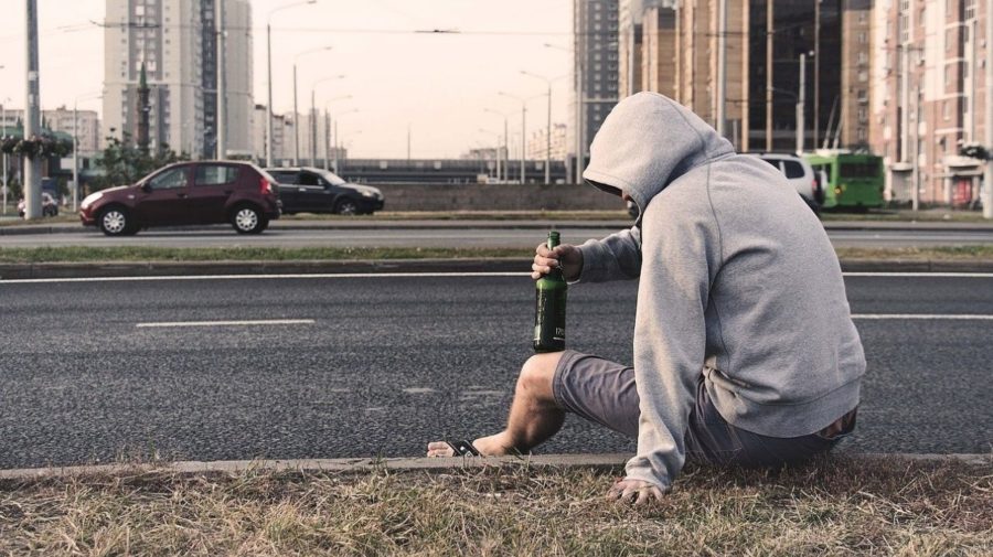 muž s fľašou alkoholu pije na ulici