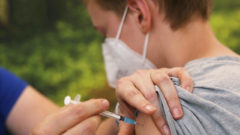 Na snímke dieťa, ktoré sa necháva očkovať proti Covidu.