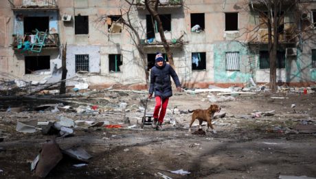 Muž kráča so psom okolo bytovky zničenej po ostreľovaní na okraji ukrajinského Mariupolu na území pod kontrolou separatistickej vlády Doneckej ľudovej republiky v utorok 29. marca 2022. FOTO TASR/AP