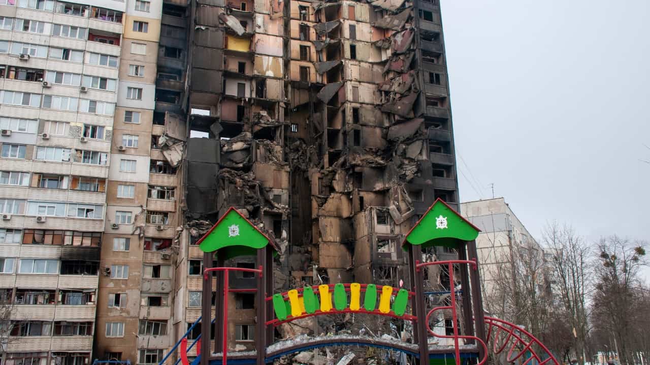 Na snímke detské ihrisko pred zničenou bytovkou po ostreľovaní počas trinásteho dňa ruskej invázie na Ukrajine 8. marca 2022 v ukrajinskom meste Charkov.