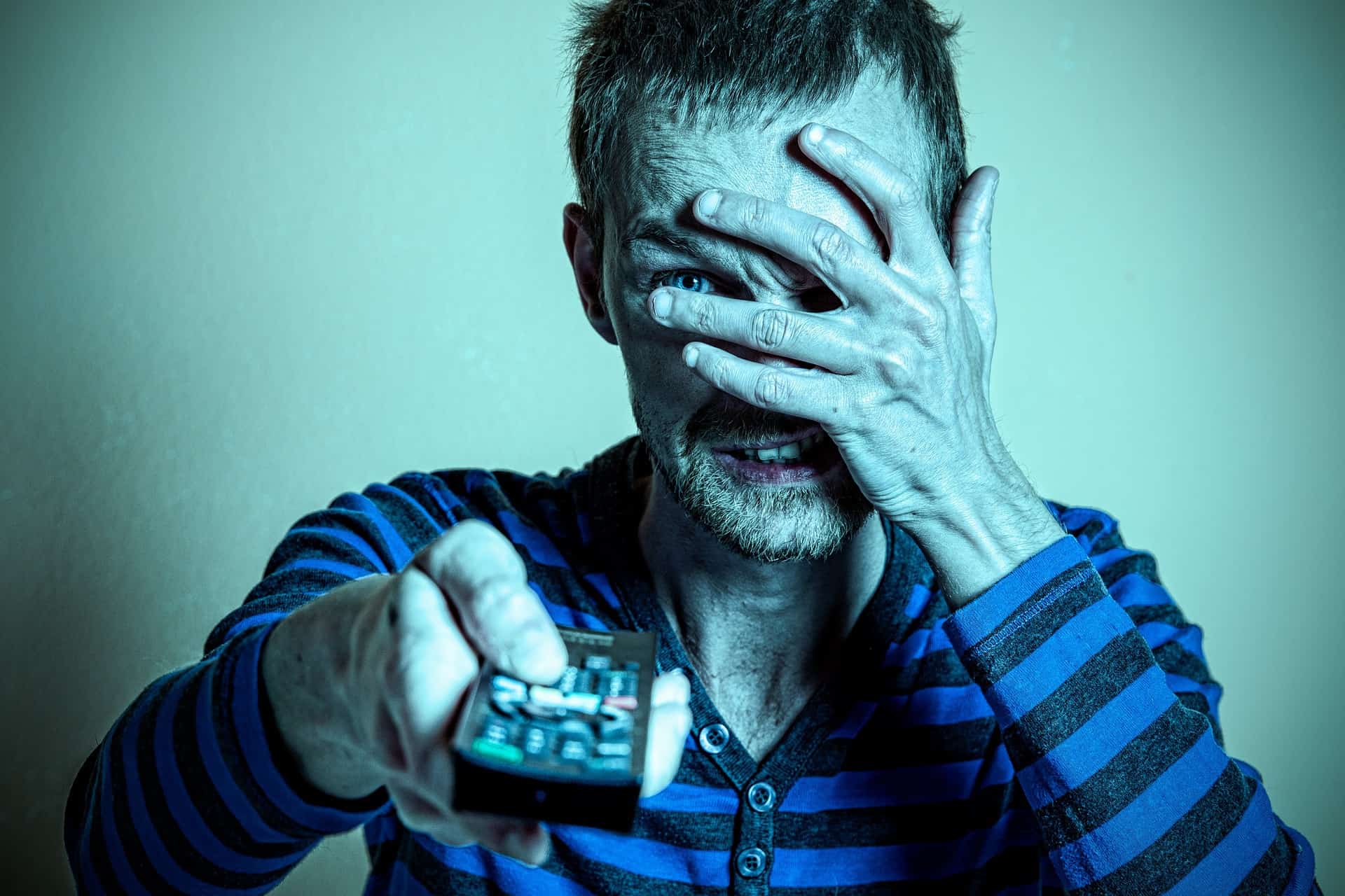 Muž so zdesením pozerá TV