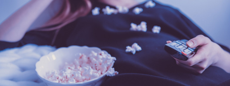 Dievča s popcornom a ovládačom od televízie v ruke