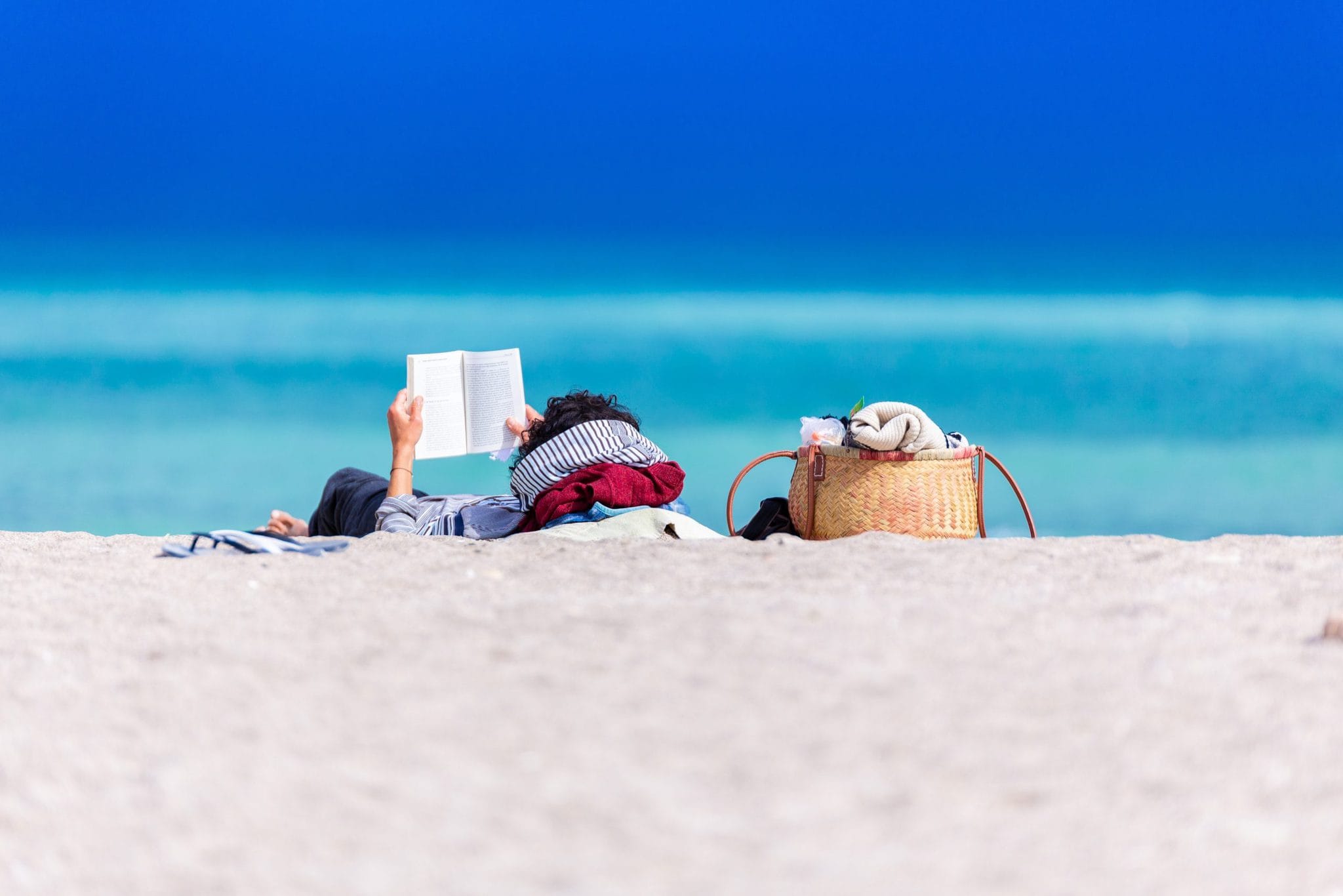 Muž leží a číta na pláži