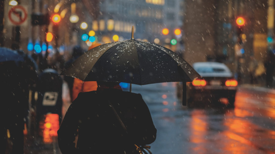 muž drží dáždnik, kým prší