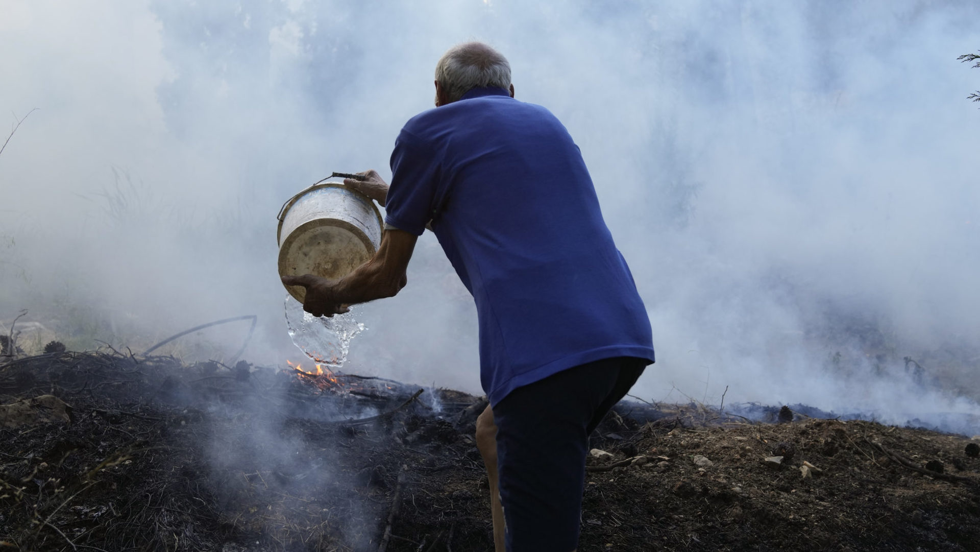 Muž v Grécku hasí požiar vedrom vody
