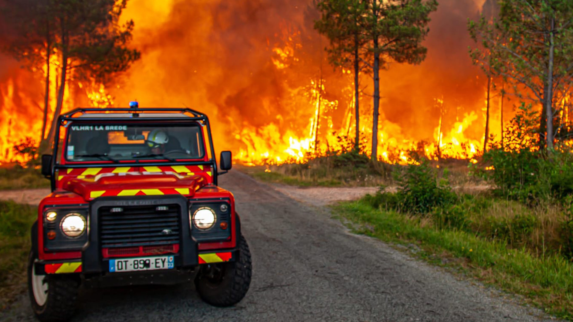 hasičské auto zaparkované pred horiacim lesom