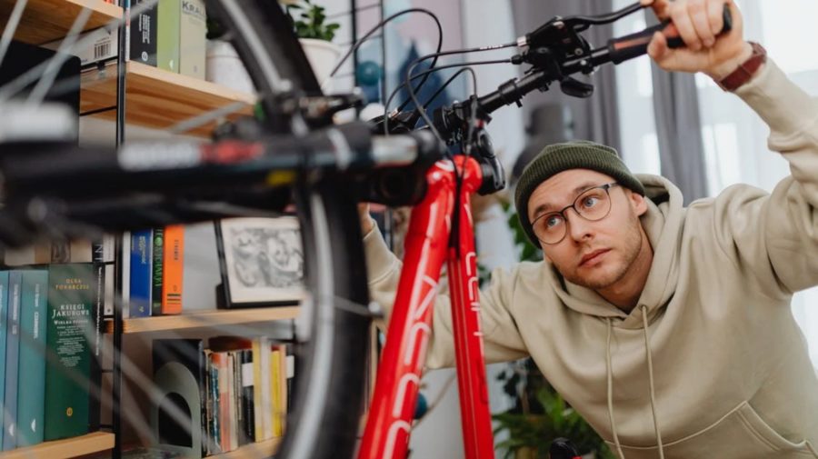 Na snímke muž, ktorý si v byte obzerá červený bicykel.
