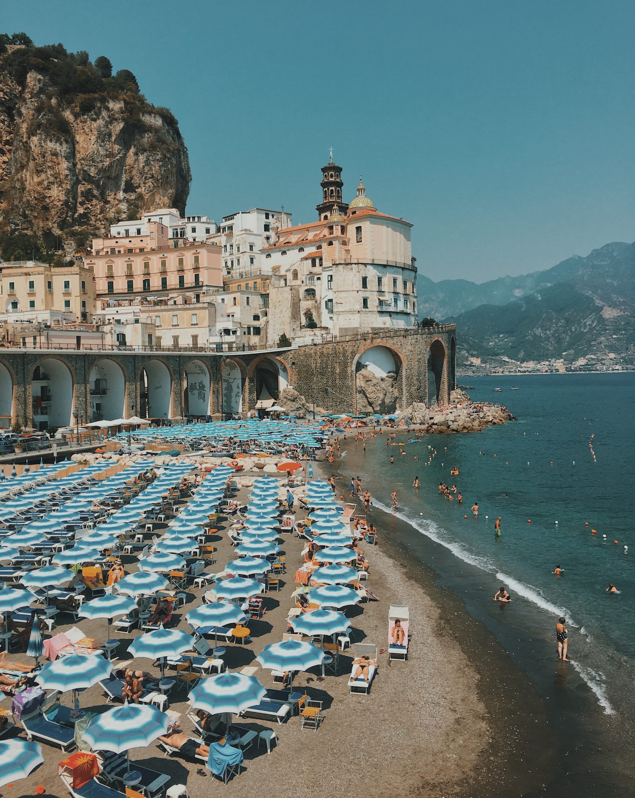 na snímke je zachytená talianska pláž so slečníkmi a krajinou v pozadí