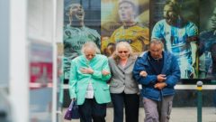 dôchodcovia držiaci sa pred obrazom mladých futbalistov