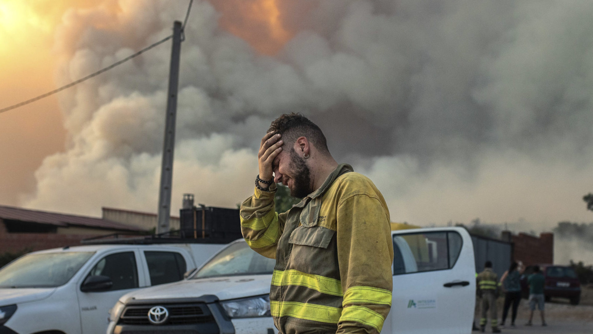 Hasič plače neďaleko hustého dymu počas lesného požiaru na severozápade Španielska