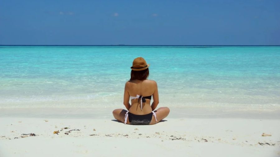 Žena na pláži si užíva dovolenku pri mori.