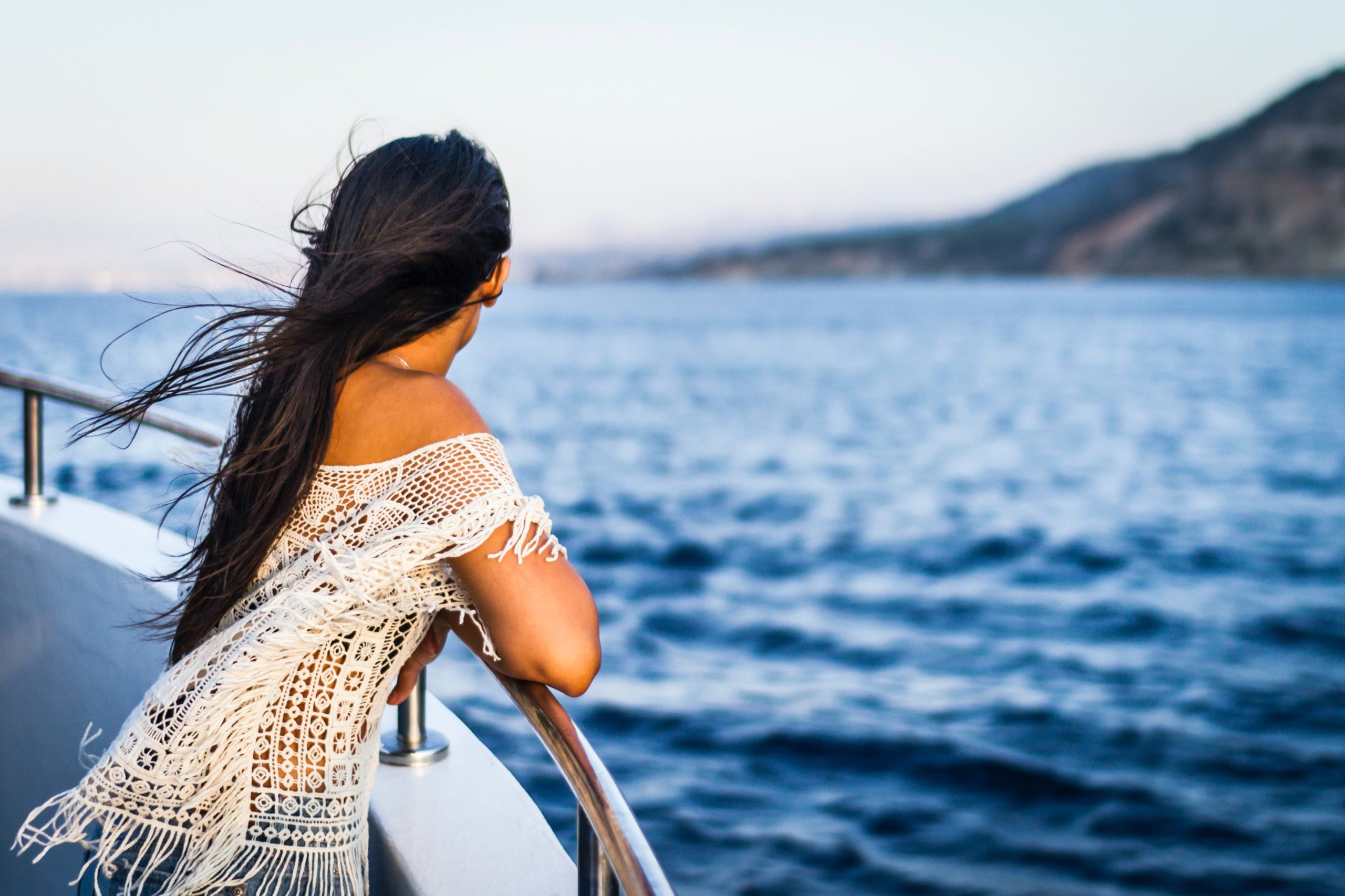 žena otočená chrbtom pozerá z lode na more