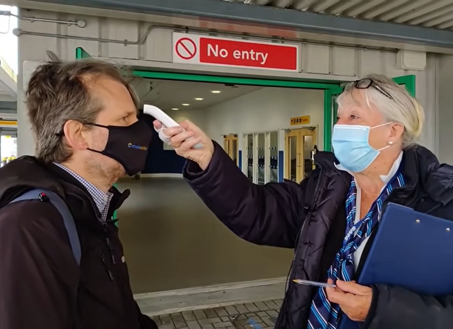 Členka posádky meria teplotu hosťovi, ktorý sa naloďuje na výletnú loď