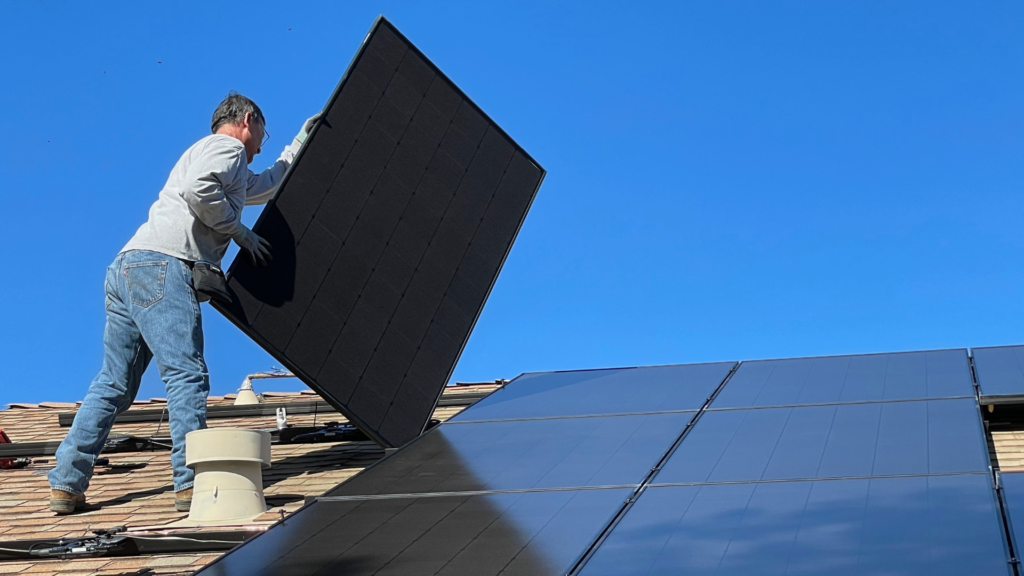 Muž na streche so solárnym panelom