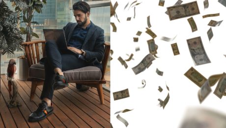 muž v obleku sedí a číta a peniaze padajú z neba