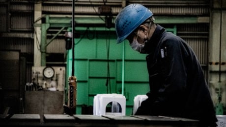 Robotník vo fabrike s bezpečnostnou prilbou v modrej farbe