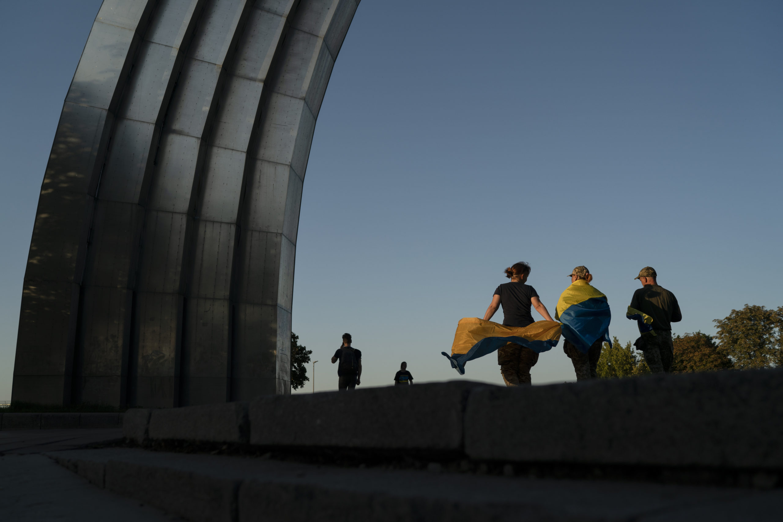 Ľudia s ukrajinskými vlajkami prechádzajú okolo pamätníka zo sovietskej éry v Deň nezávislosti krajiny v Kyjeve,