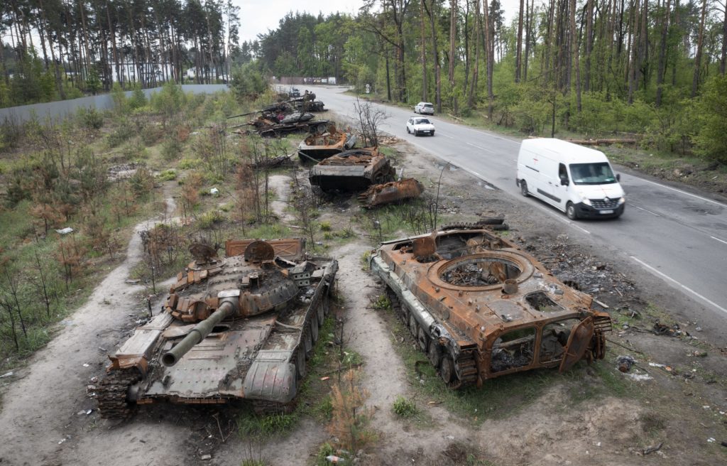 Autá prechádzajú okolo zničených tankov pri Kyjeve