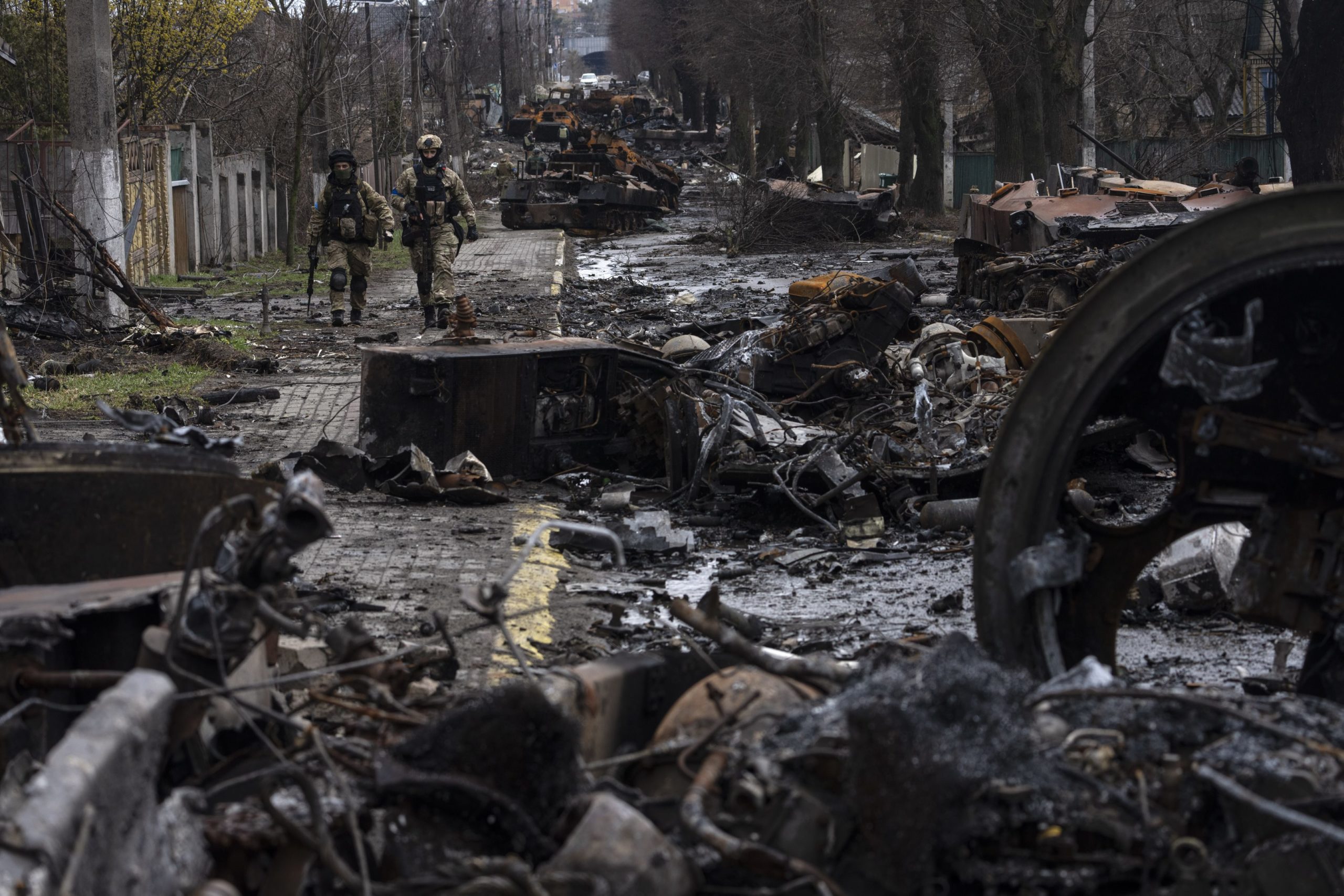 Vojaci v Buči kráčajú pomedzi zničené ukrajinské tanky