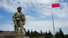 ruský vojak na okupovanom území. V pozadí sovietska vlajka
