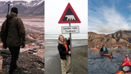 Muž pozerá z hory s puškou, žena drží tabuľu, ktorá upozorňuje na medvede, kajakovanie vo fjorde