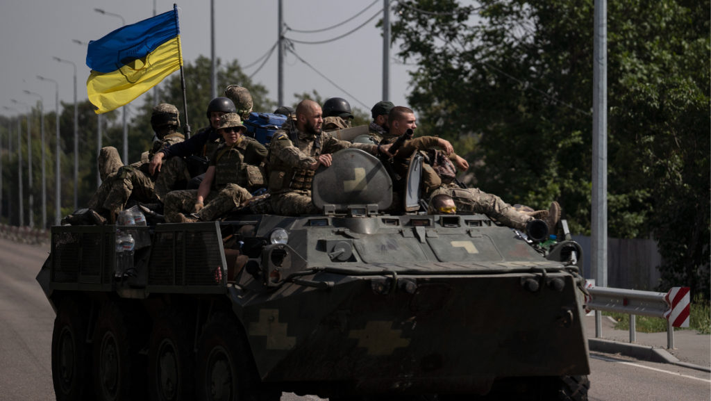 Fotografia zachytáva ukrajinských vojakov s vlajkou.