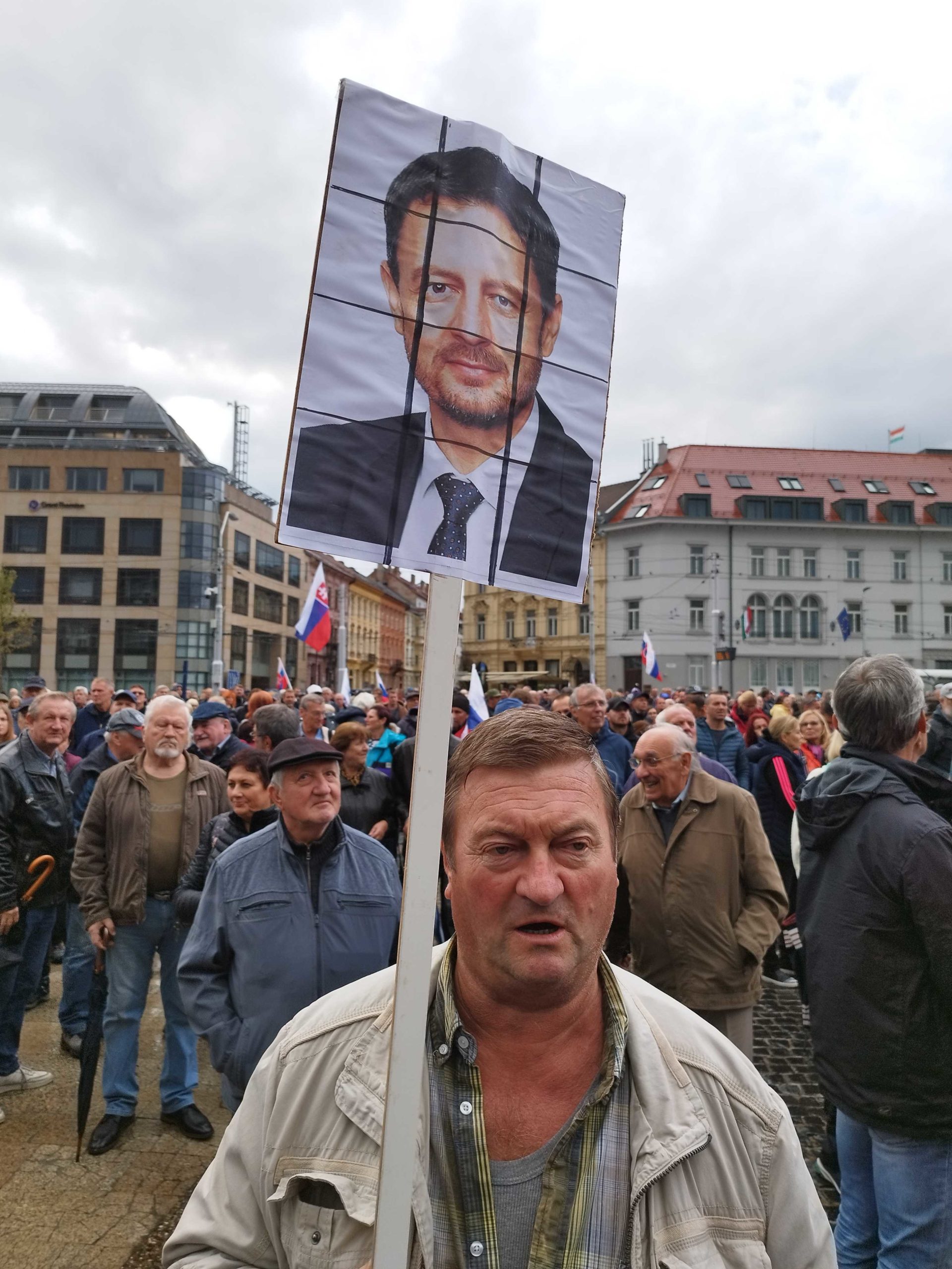Účastník protestu pred prezidentským palácom s banerom tváre Eduarda Hegera