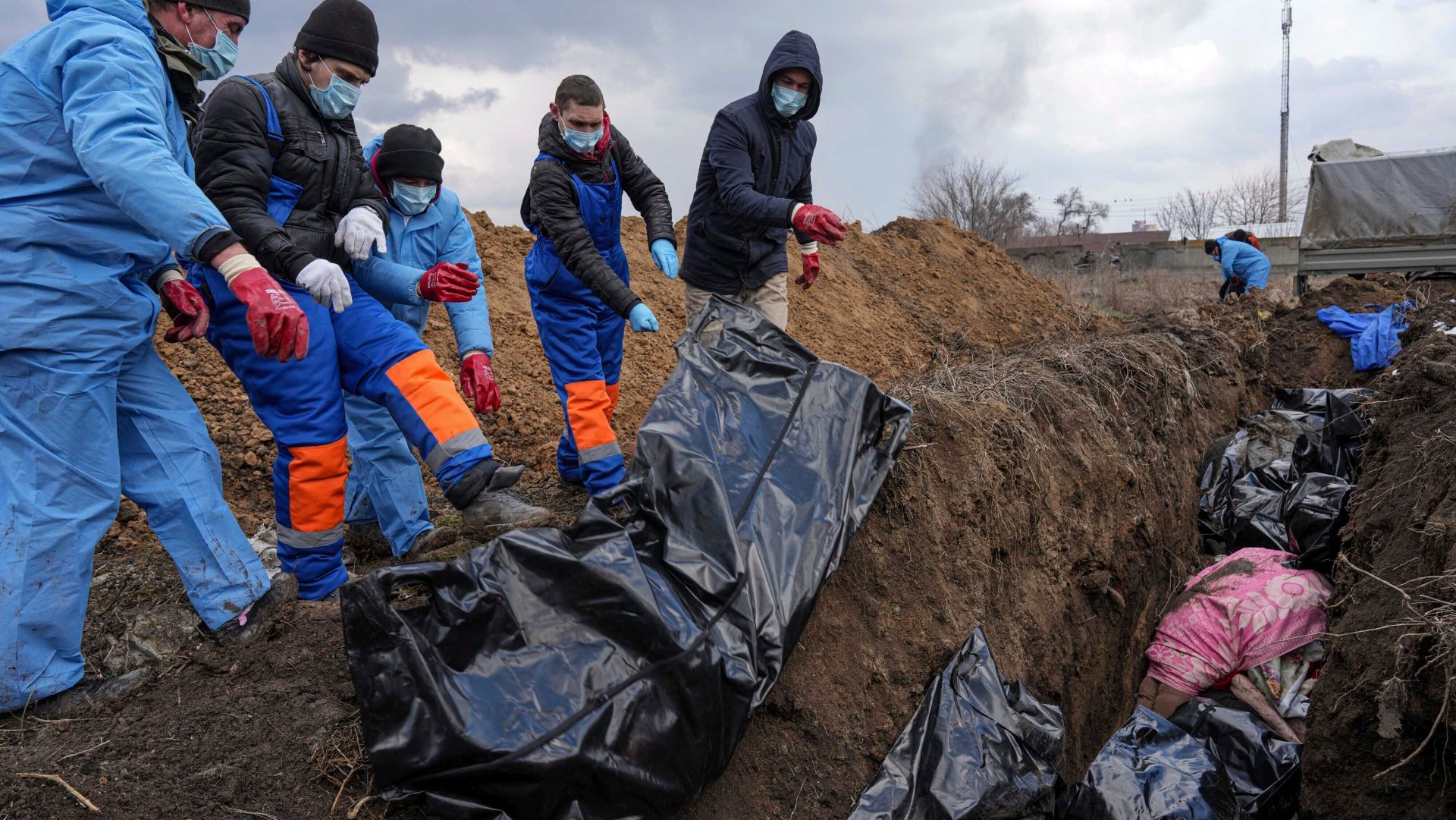 ukrajinci ukladajúci telá do masového hrobu