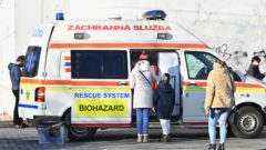 Na snímke je sanitka a ľudia, ktorí sa nechávajú testovať na Covid.