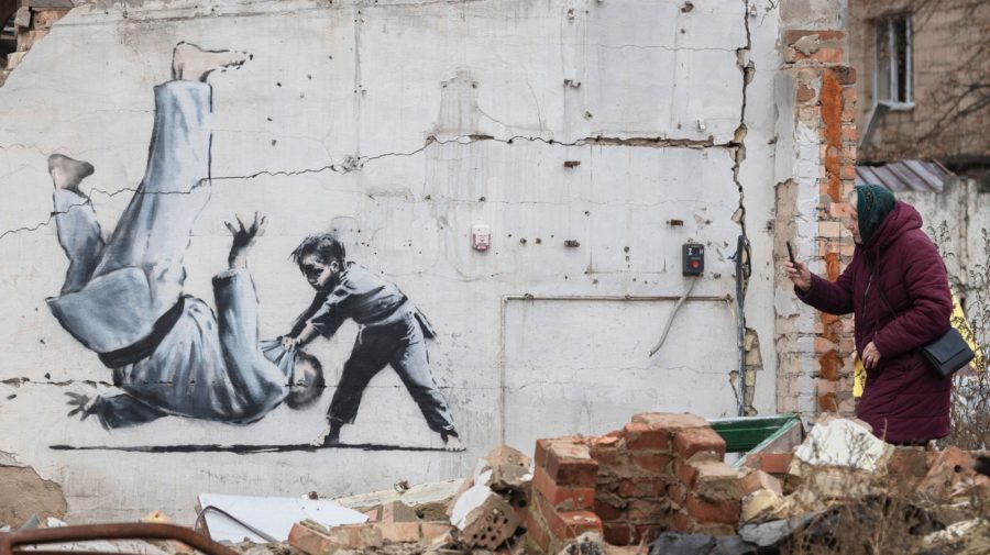 Na snímke dielo britského streetartového umelca Banksyho zobrazuje dieťa, ktoré v zápase v džude vyhráva nad ruským prezidentom Vladimirom Putinom, na budove poškodenej ostreľovaním 13. novembra 2022 v ukrajinskom meste Boroďanka.