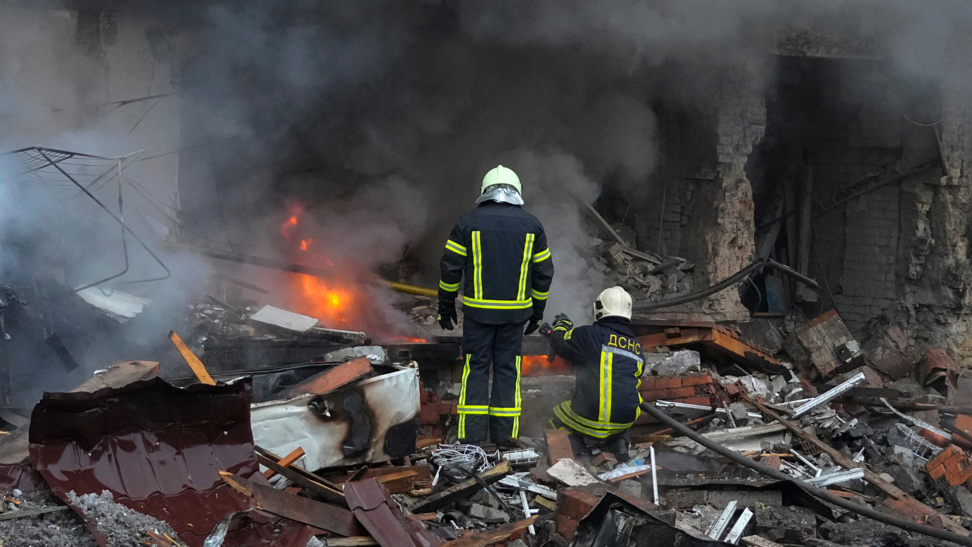 Hasiči pred ruinami bytovky