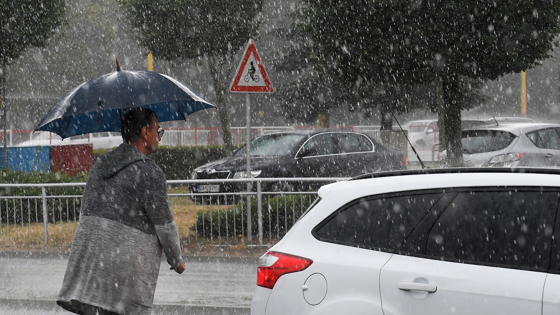 Muž s dáždnikom kráča v lejaku