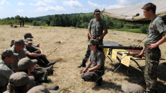 Vojaci na výcviku učia mladších študentov, ktorí sedia na zemi.