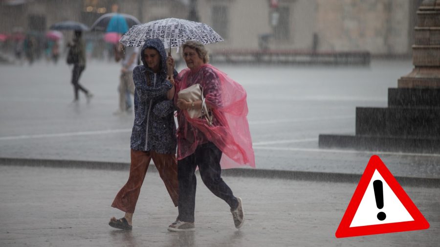 Ženy v pršiplášťoch sa schovávajú pod dáždnikom pred dažďom