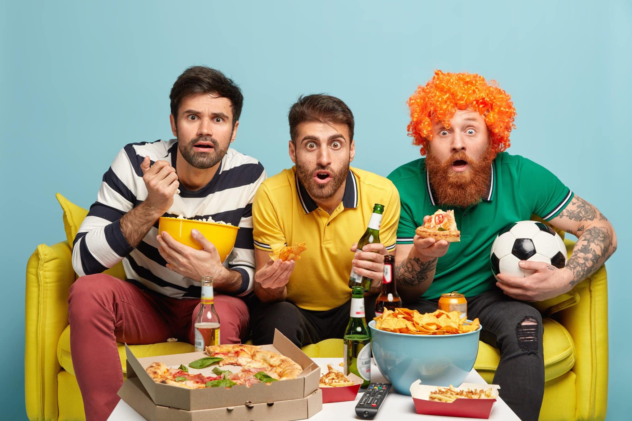 excited-three-male-friends-watch-sport-tournament-have-bated-breath-during-dangerous-moment-bite-crisps-popcorn-pizza-sit-yellow-sofa-living-room-soccer-fans-with-beer-football-supporter