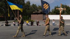 Ukrajinskí vojaci nesú vlajky a kríž