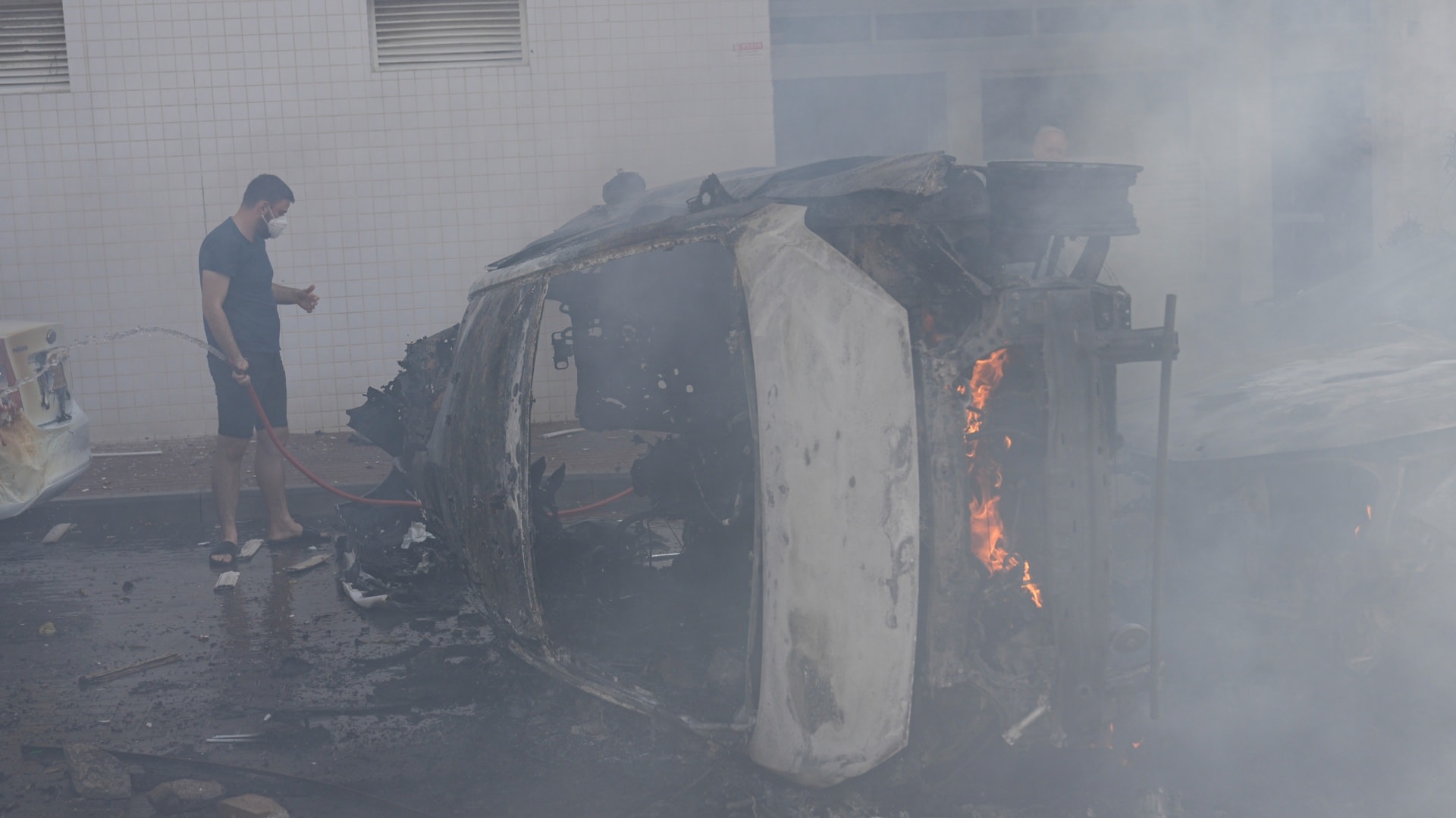 Muž hasí horiace auto