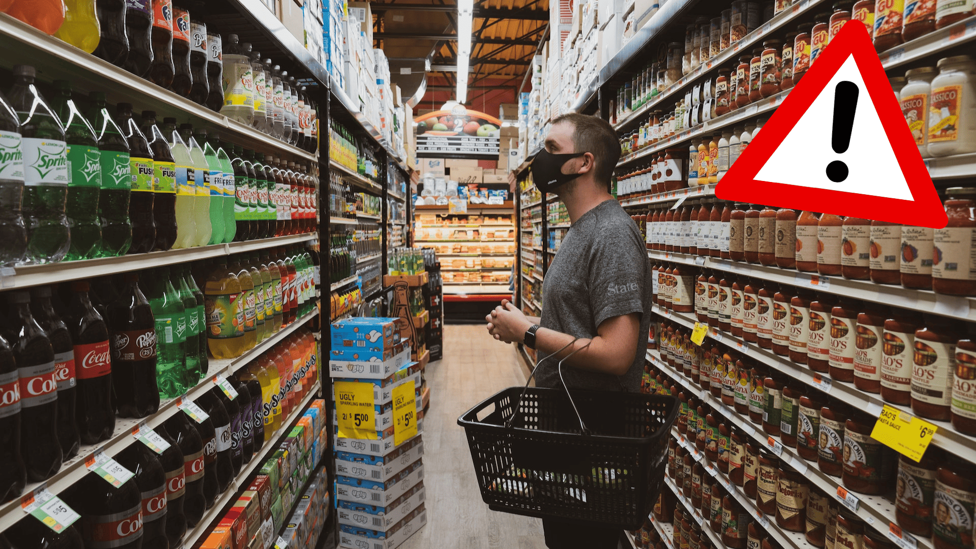 Muž v rúšku stojí pred regálom s nápojmi.