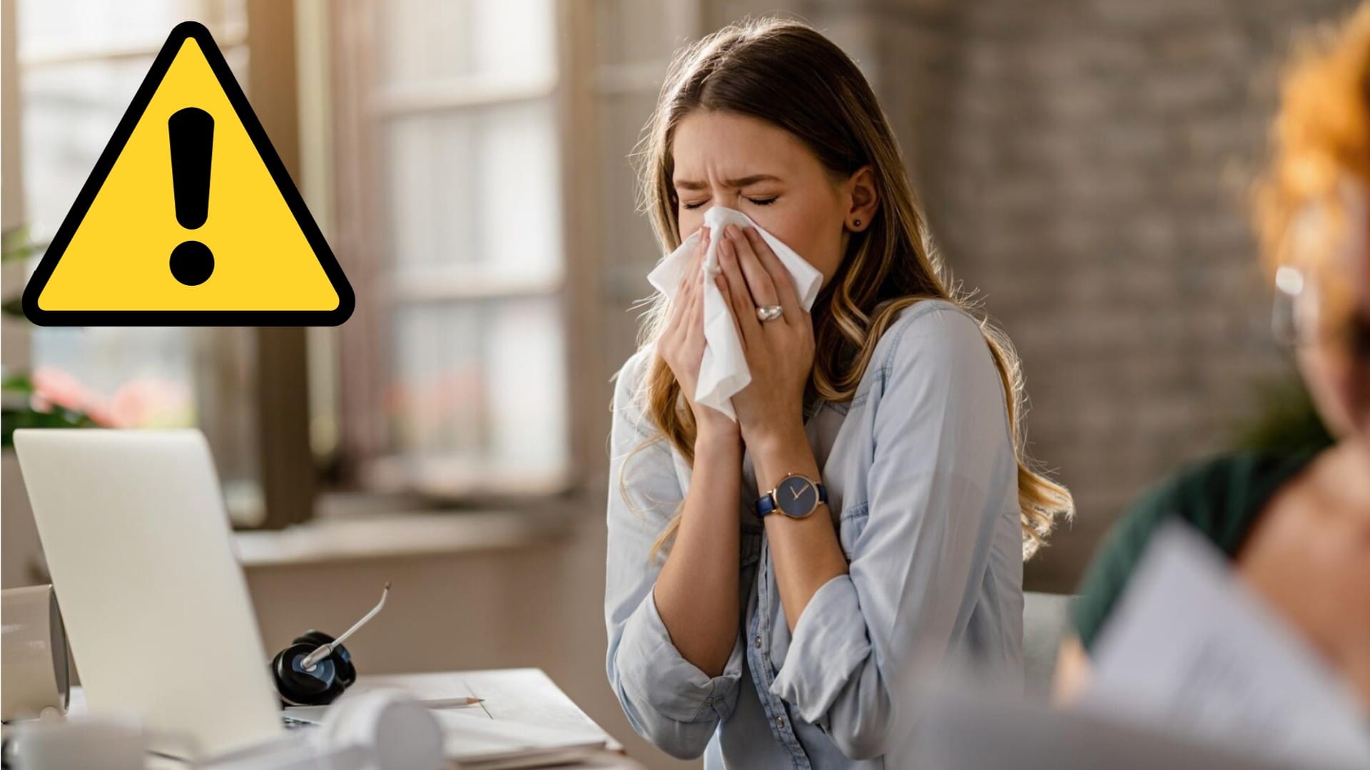 Žena si smrká nos do servítky za stolom v práci.