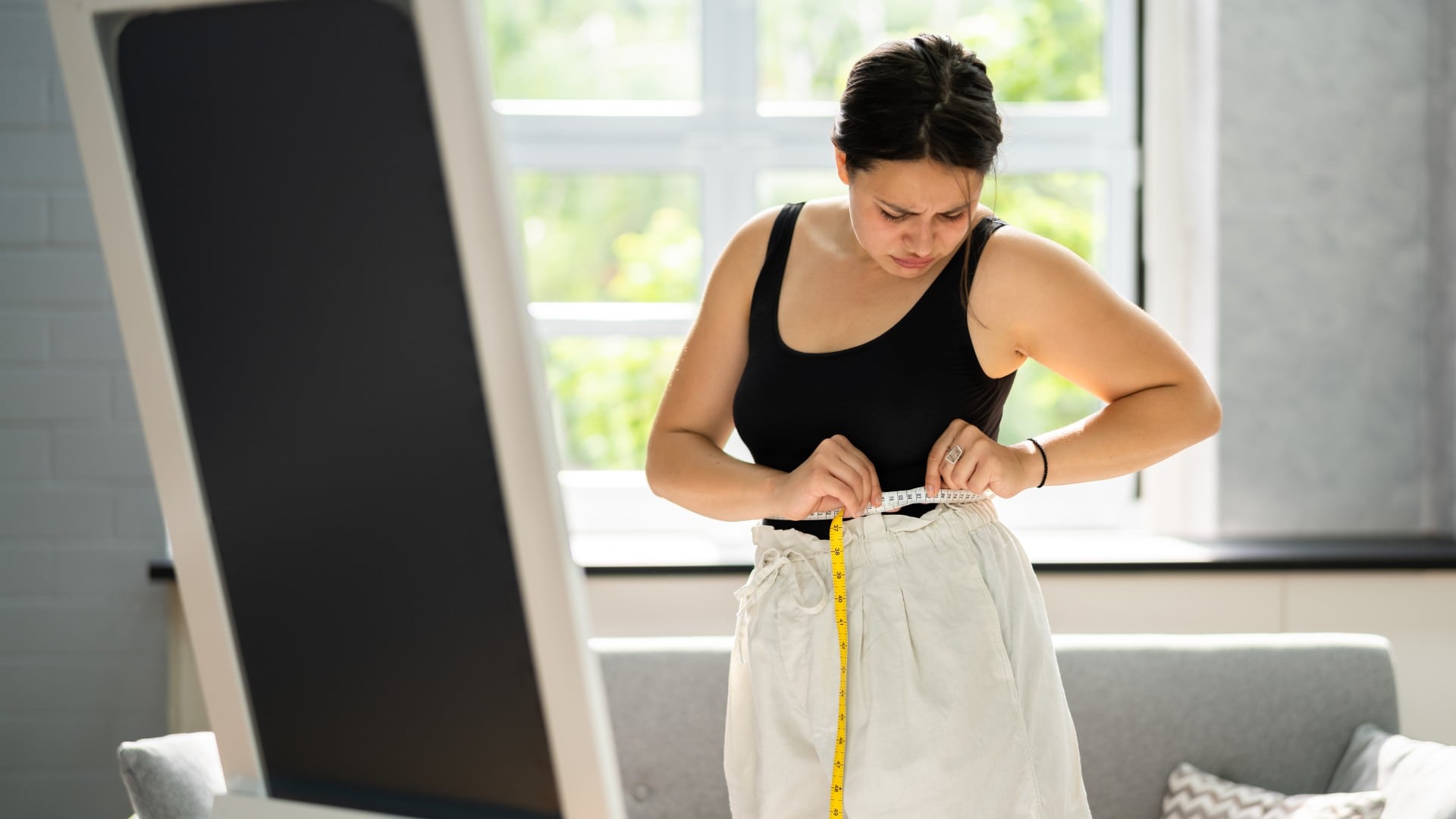 Na snímke žena merajúca si obvod pásu.