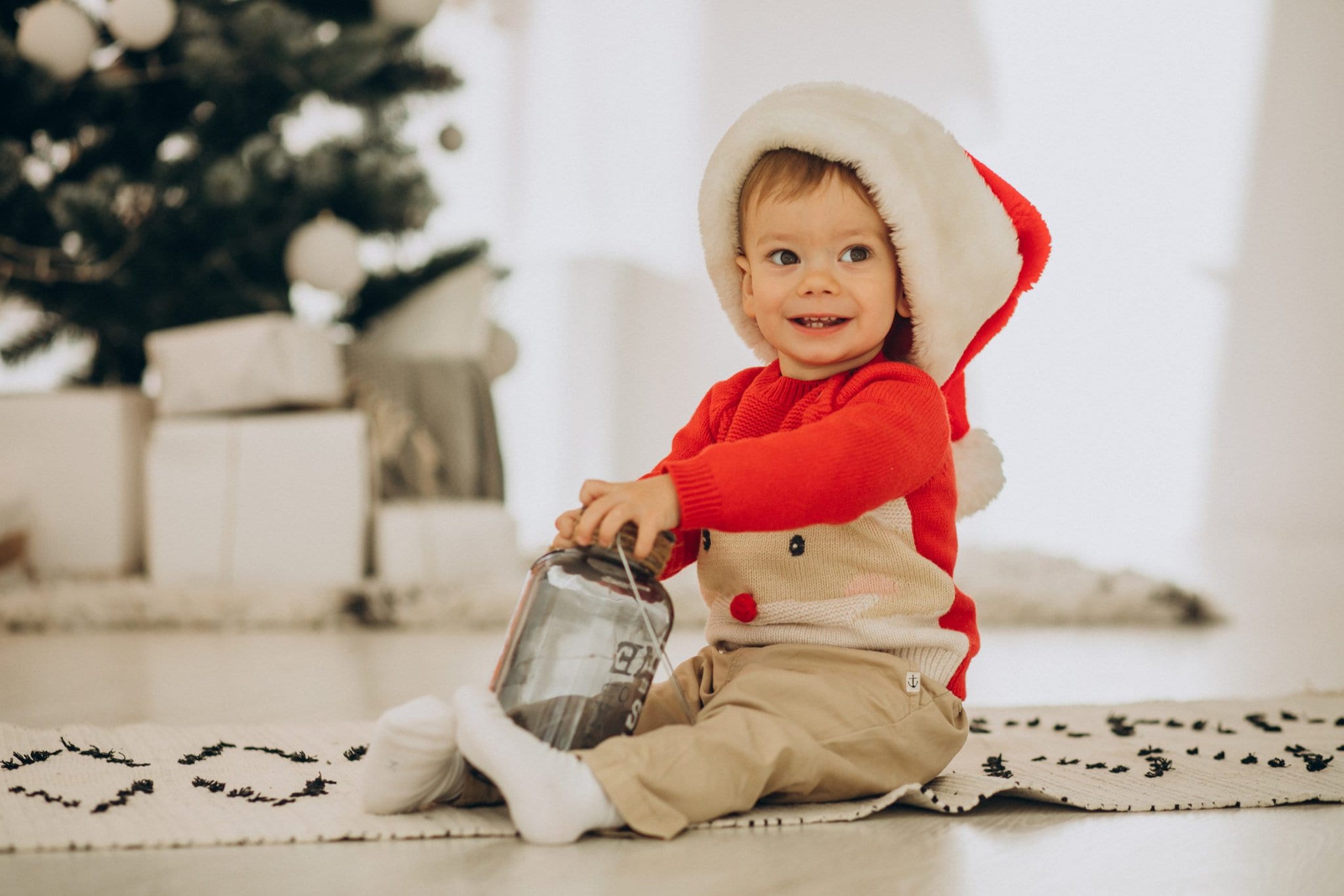 Dieťa vo vianočnej čiapke pri vianočno stromčeku