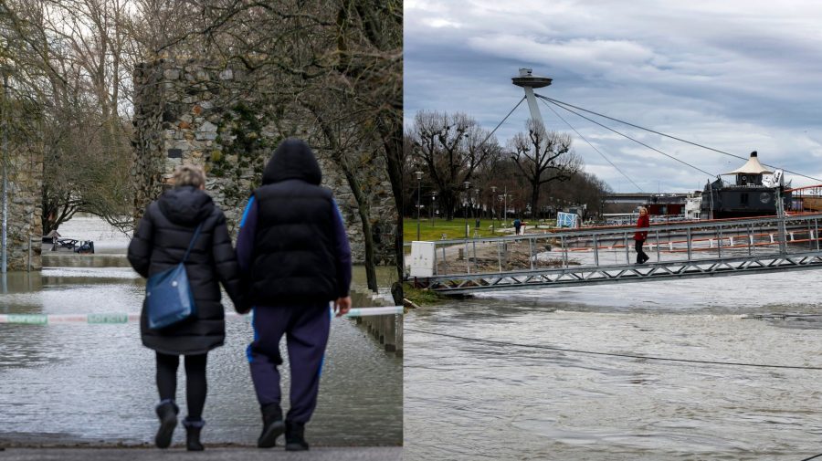 Ľudia kráčajú popri zaplavenej ulici a pohľad na vysokú hladinu rieky Dunaj na Tyršovom nábreží v Bratislave.